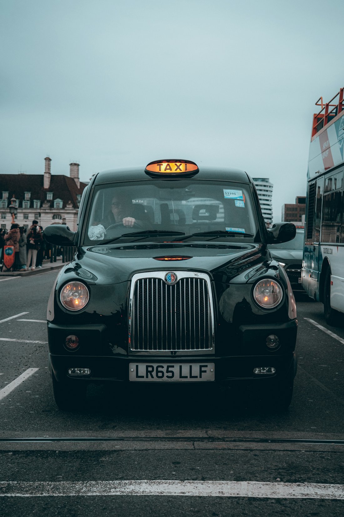 A black London taxi waiting in traffic on a city street
